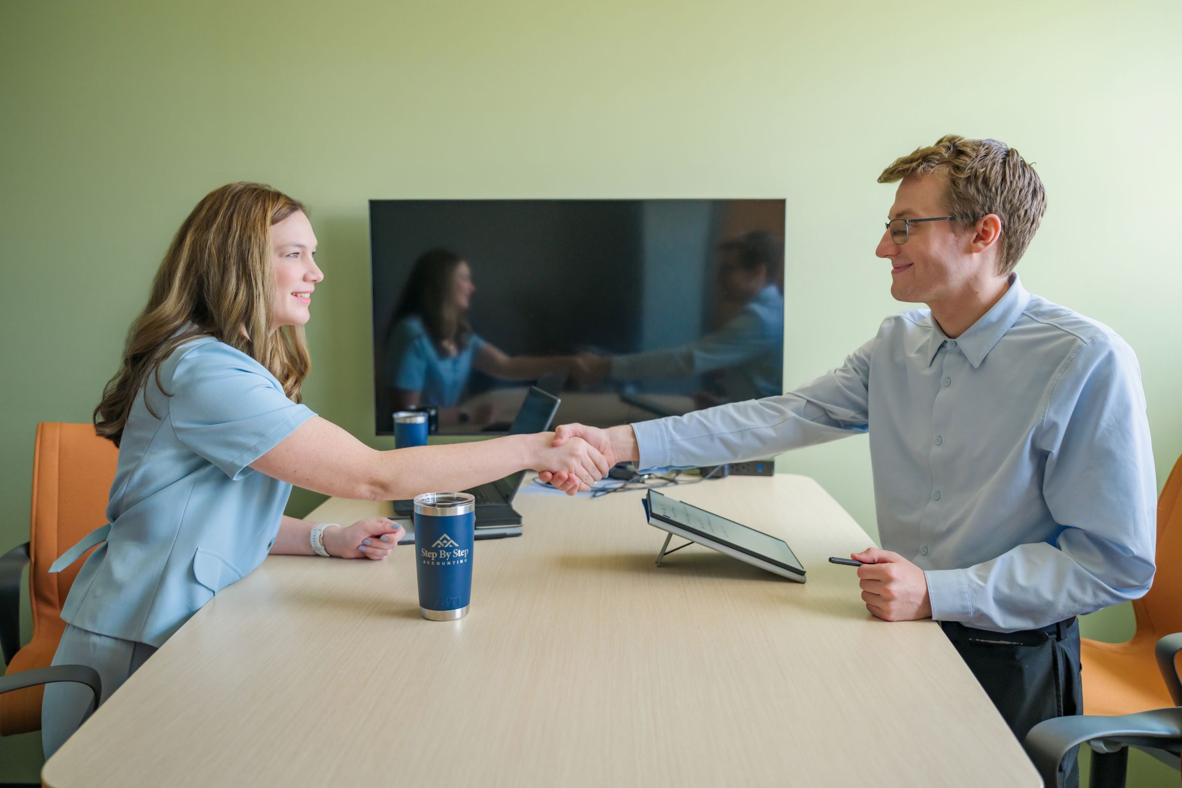 A woman and man shake hands at a professional accounting firm.